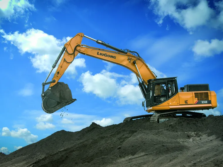 Excavadora LiuGong 936E sobre un montículo de tierra con el brazo extendido bajo cielo azul